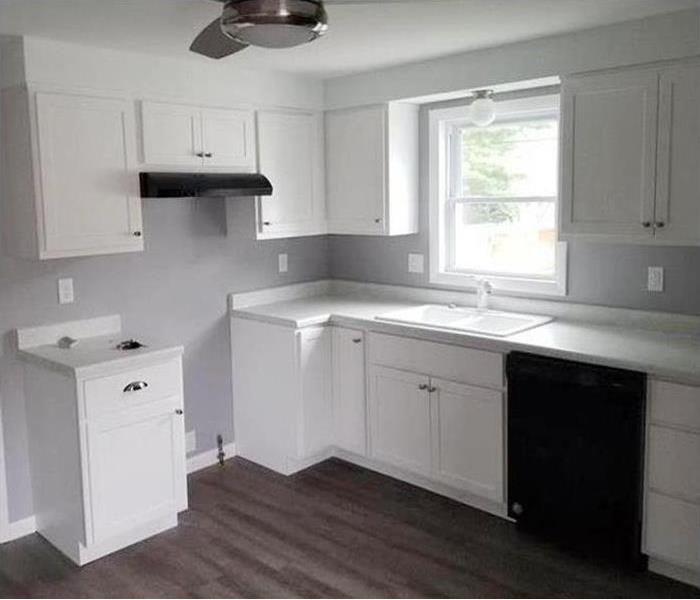 a brand new kitchen with white cabinets and gray flooring
