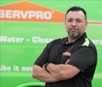 Middle-aged man with dark hair and slightly gray, goatee beard and SERVPRO T-shirt, standing next to a SERVPRO truck