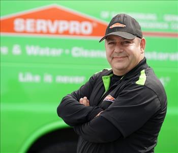 Middle-aged man in SERVPRO ball cap and black fleece, standing by a SERVPRO truck