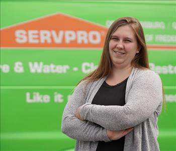 female employee wearing a black SERVPRO shirt standing next to a SERVPRO truck