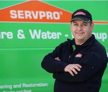 Middle-aged man in SERVPRO ball cap and black fleece, standing by a SERVPRO truck