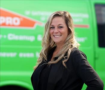 female employee wearing a black shirt standing next to a SERVPRO truck