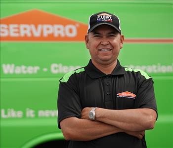 Middle aged, clean shaven man in ball cap and SERVPRO T-shirt standing next to a SERVPRO truck