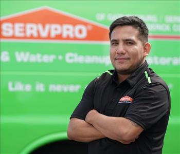 male employee wearing a black SERVPRO shirt standing next to a SERVPRO truck