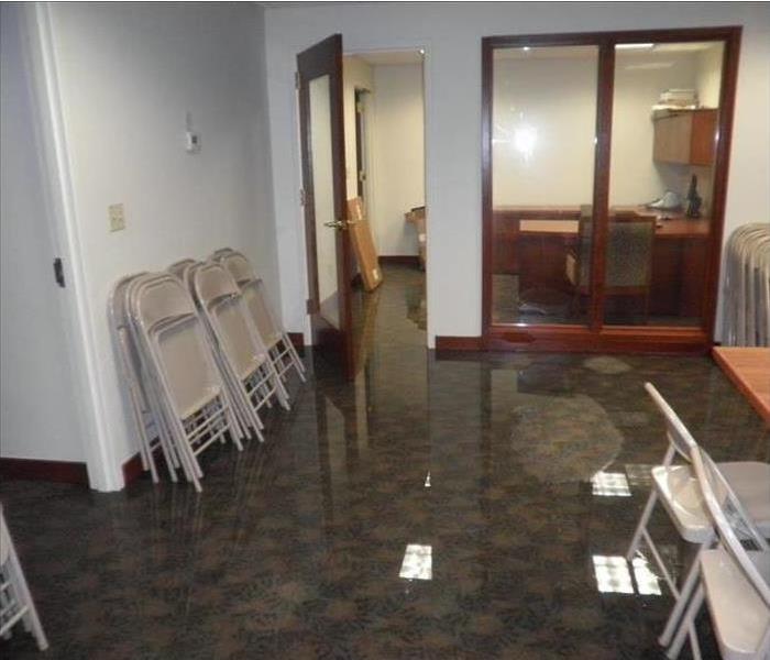 water covering carpet in an office area, ceiling lights reflected