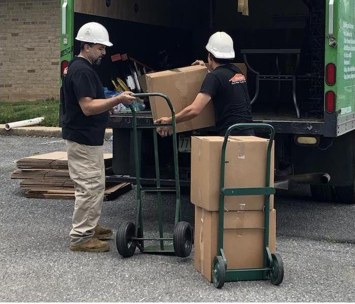Two SERVPRO technicians moving boxes from a fire damaged house into a truck