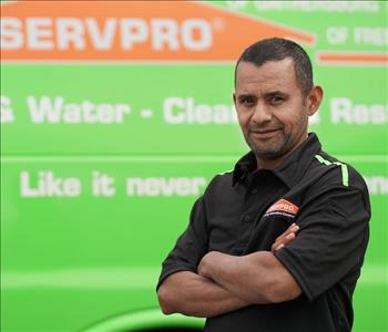 male employee wearing a black SERVPRO shirt standing next to a SERVPRO truck