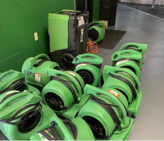 SERVPRO fans and dehumidifiers lined up in a warehouse